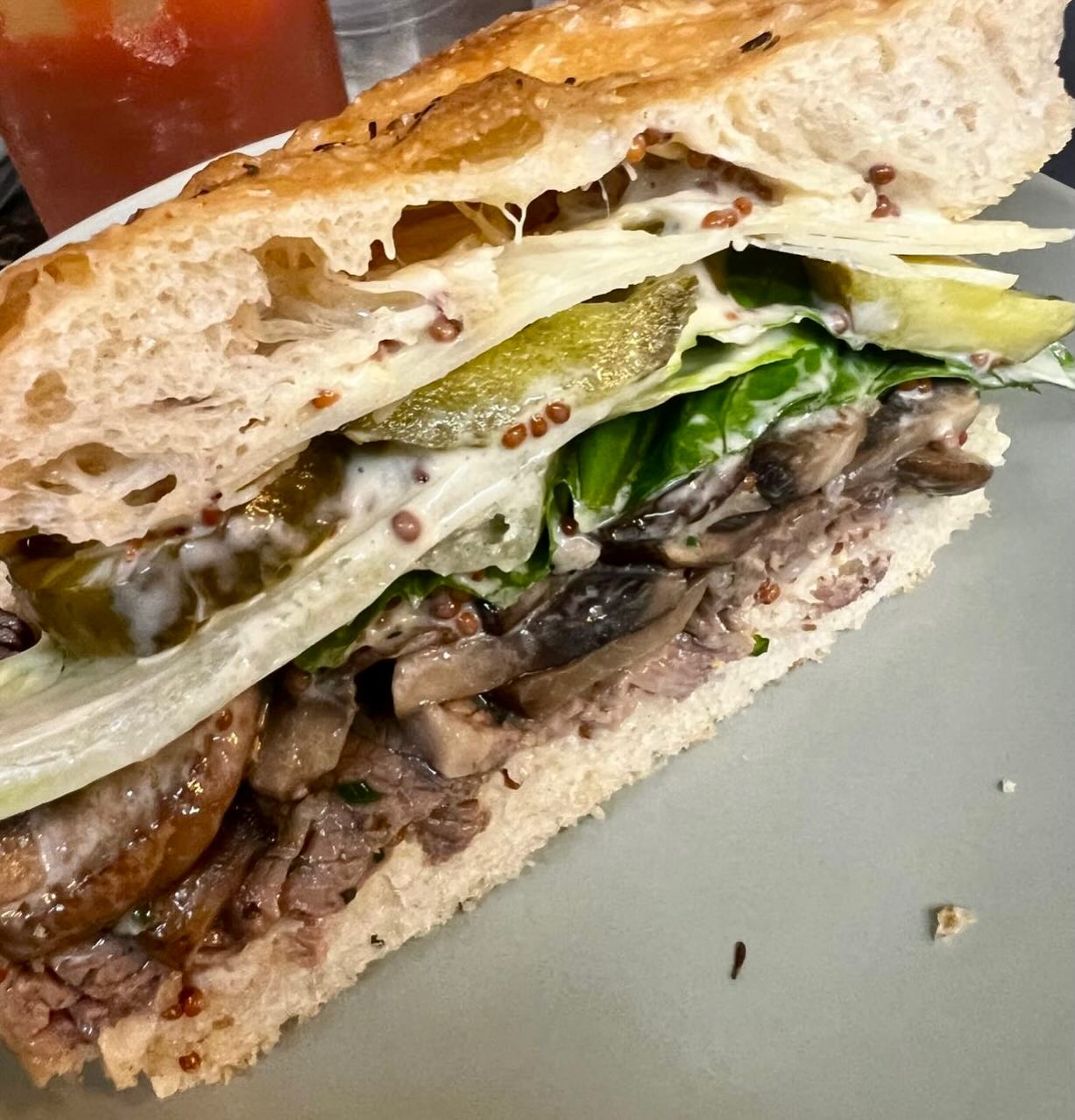 Gourmet deli sandwich with roast beef, mushrooms and melted cheese